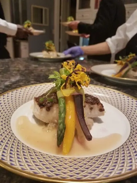 Gourmet plated fine dining dish with grilled fish, colorful vegetables, and elegant sauce, showcasing global fusion and Michelin-level cuisine