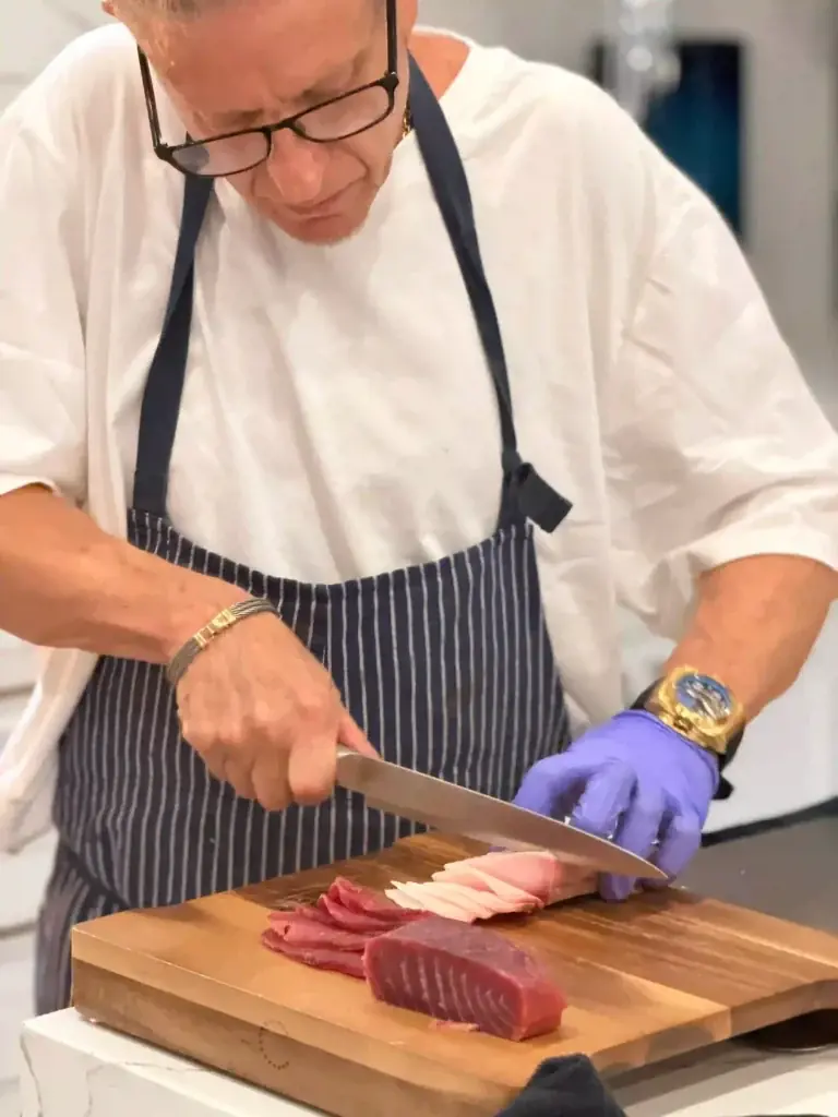 Executive chef David Rosov slicing fresh tuna on a cutting board for a private dining experience in Palm Beach