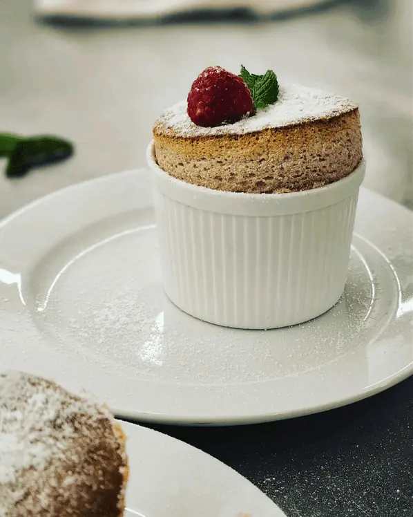 Luxury soufflé dessert with powdered sugar, fresh raspberry and mint, served in a white ramekin by Palm Beach private chef